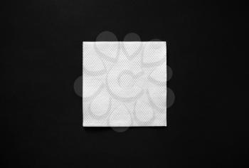 Blank white paper napkin on black background with copy space. Flat lay.