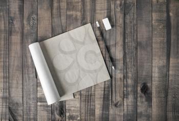 Open square format brochure or notepad, pencil and eraser on wooden table background. Flat lay.