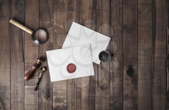 Vintage postal stationery. Blank envelope, sealing wax, stamp, spoon, magnifier, compass and postcard on wood background. Responsive design mock up. Flat lay.