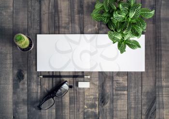 Blank stationery template. Notebook, pencil, eraser, glasses and plants on wooden background. Flat lay