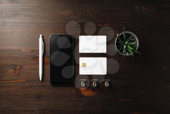 Blank business template. Smartphone, business card, bank card, pen and plant on wood table background. Flat lay.