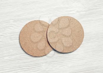 Photo of two cork beer coasters on light wood table background. Flat lay.