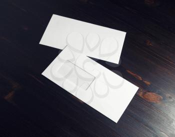 Two blank paper envelopes with window on dark wood table background. Front and back side. Copy space for text.