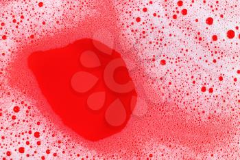 Foam with bubbles on red background. Shampoo or detergent in water. Flat lay.