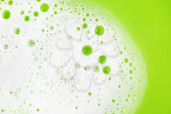 Soap foam with bubbles on green background. Soap sud in water. Detergent concept. Flat lay.