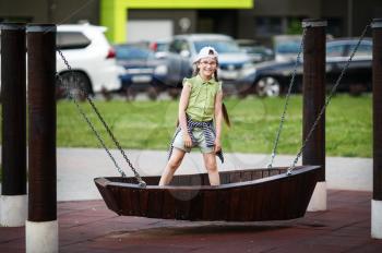 Child girl on a swing in the form of a boat. Selective focus.