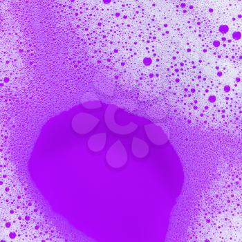 Foam with bubbles on purple background. Detergent in water. Soap sud. Flat lay.