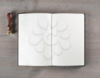 Blank book and stamp on wooden background. Flat lay.