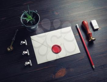 Retro postal stationery. Blank envelope with wax seal, stamp, pencil, eraser, plant and spoon on wooden background.