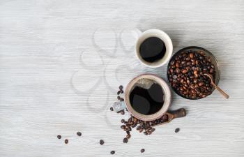 Photo of coffee cups and coffee beans on light wooden background. Copy space for your text. Top view. Flat lay.