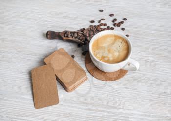 Blank kraft paper business cards, coffee cup, roasted coffee beans on light wooden background.