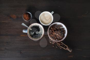 Cups of coffee, coffee beans and ground powder on wooden background. Flat lay.