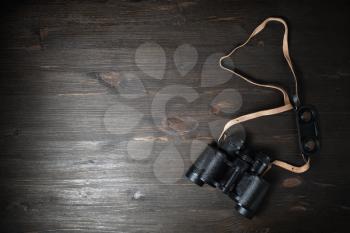 Black military binoculars on wooden background. Lot of copy space for your text. Flat lay.