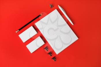 Blank corporate stationery set on red paper background. Corporate identity template. Responsive design mockup. Top view. Flat lay.