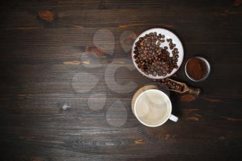 Coffee cup, coffee beans and ground powder on wooden background. Copy space for your text. Top view. Flat lay.