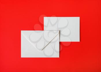 Two blank paper envelopes on red paper background. Back and front. Top view. Flat lay.