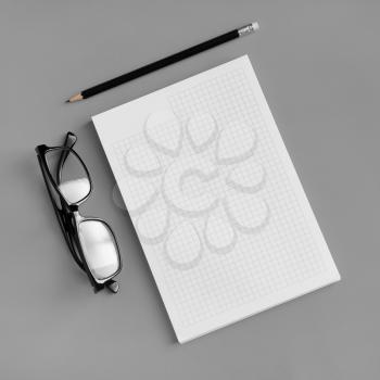 Blank stationery set. Copybook, pencil and glasses on gray paper background. Template for placing your design. Flat lay.