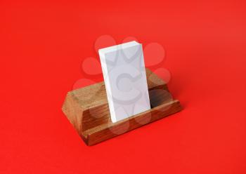 Blank business cards on wooden holder on red paper background.