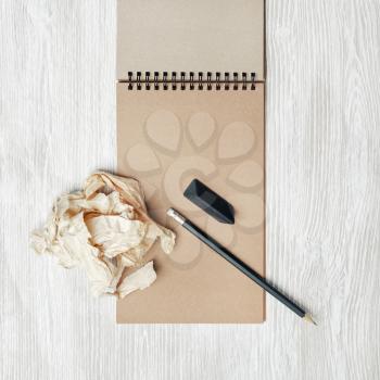 Vintage stationery set. Blank notepad, pencil, eraser and crumpled paper on light wooden background. Top view. Flat lay.