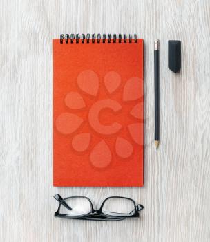 Notepad, glasses, pencil and eraser on light wooden background. Branding mock up. Flat lay.