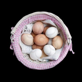 Eggs in wicker basket on black background. Top view. Flat lay.