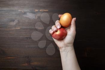 Easter eggs in female hand on wooden background.