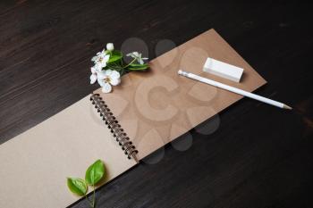 Stationery and flowers. Blank kraft sketchbook, pencil, eraser and spring flowers on wooden background.