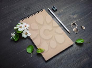 Photo of blank kraft paper notepad, pencil, sharpener and spring flowers on wood table background.