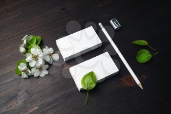 Blank business cards, pencil, sharpener and spring flowers on wooden background.