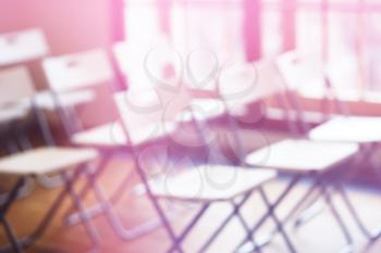 Classroom with empty chairs and pink bokeh background

