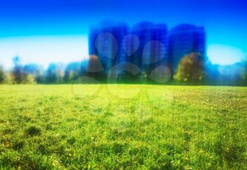 Green lawn with three blurry buildings background