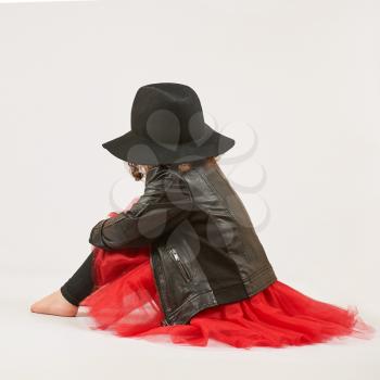 Little girl with black hat sitting and turned away