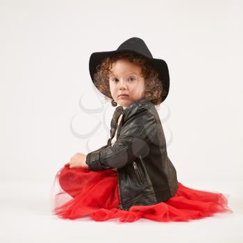 Little girl with black hat sitting and looks