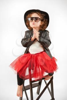Little girl with black hat sitting on a high stool and dabbles