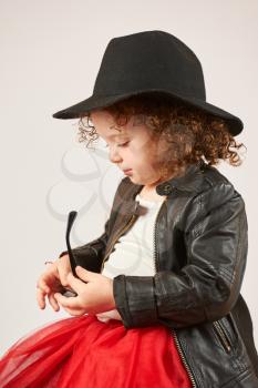 Little girl with black hat sitting looking over sunglasses
