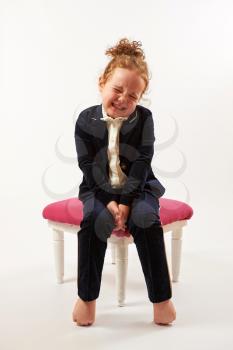 Little girl in black suit sitting on a rose stool