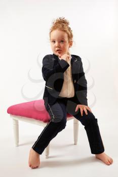 Little girl in black suit sitting and pouting