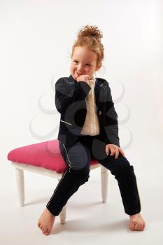 Little girl in black suit sitting and pouting
