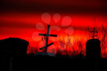 Christian cross silhouette with the bloody sunset as background