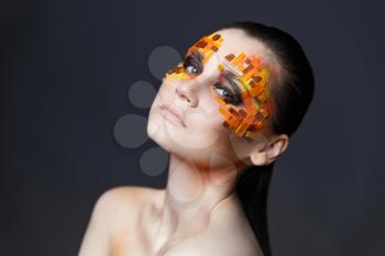 Portrait of a girl with an original make-up. Beauty close-up. Orange and red rhinestones on a face