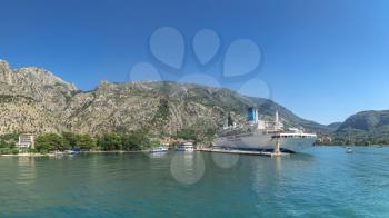 Kotor, Montenegro - 07.11.2018.  View from the sea to the cruise liner at the pier of the old town of Kotor and fortification wall around the city in Montenegro in a sunny summer day