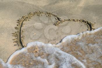 Heart drawn on the beach sand. heart symbol on the sand washed by the sea wave.