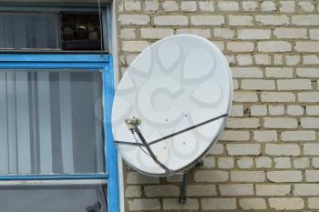 Satellite antenna on the wall near the window. Satellite television.