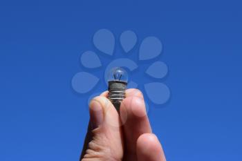 Bulb on 3 volts in a hand against the sky. Redkoispolzuyemy lamp.