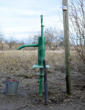 Hand pump leading to an artesian well. Pumping water for watering the garden.