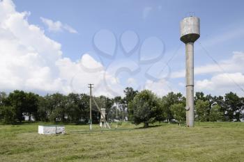 Silver Water Tower among green grass and trees.