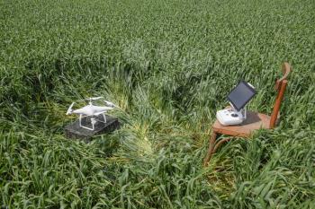 Quadrocopters on a plastic box among the wheat stalks and control panel with a clipboard on a chair. Preparation quadrocopter to fly.