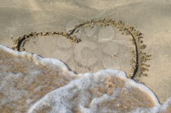 Heart drawn on the beach sand. heart symbol on the sand washed by the sea wave.