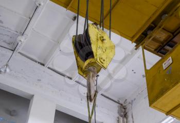 Hoist with winch and hook. A tool for moving goods in a production room. Mechanization of labor.