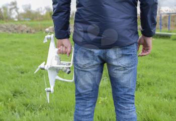 A man with a quadrocopter in his hands. White kvadrokopter prepare for flight.